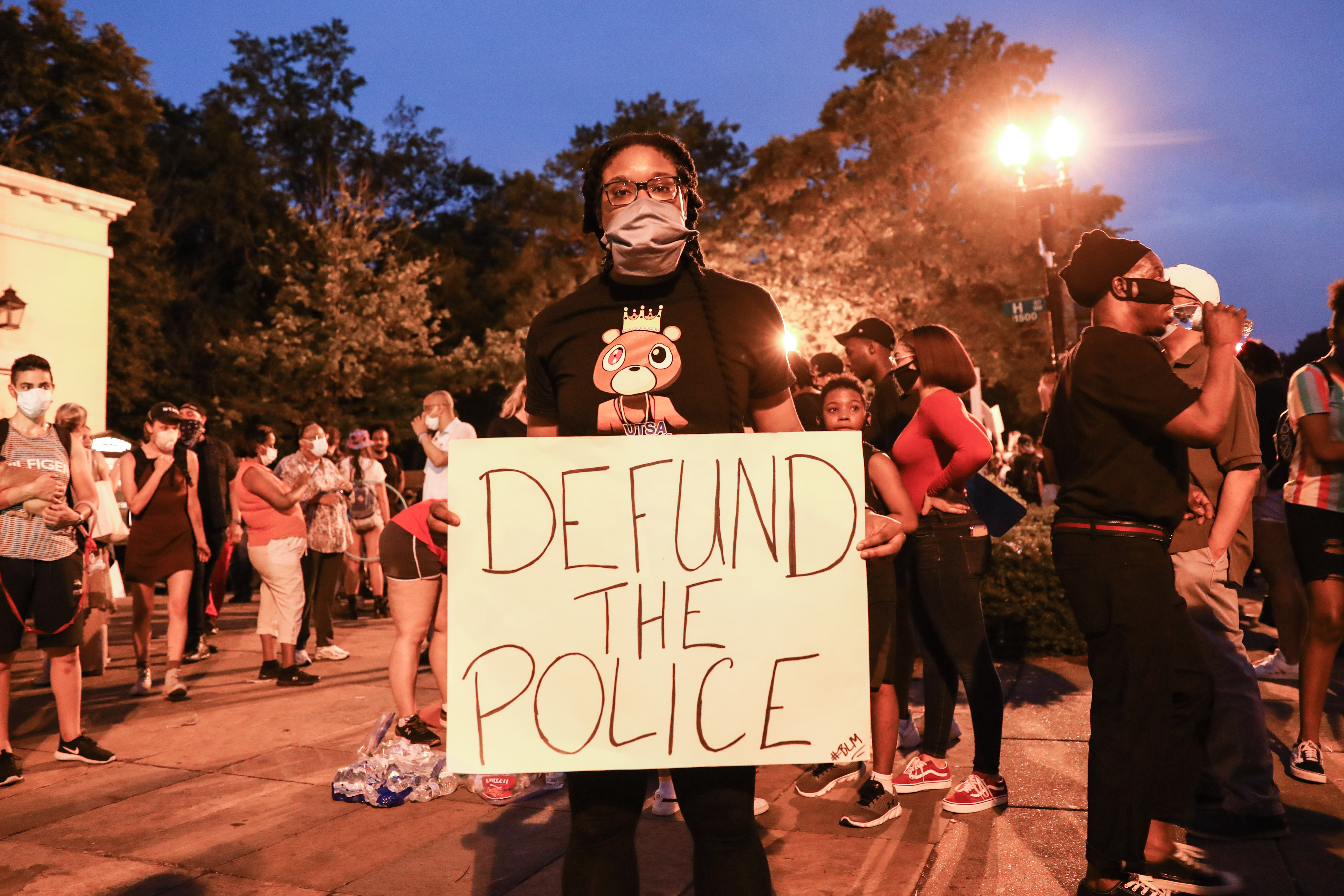 A protester holds a "Defund the Police" sign during a protest nea...