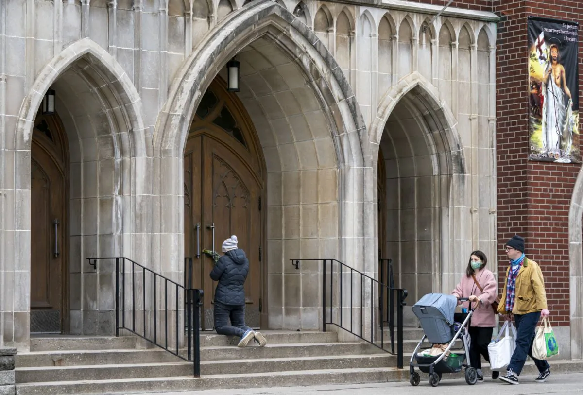 A woman prays on the steps outside St. Casimir’s Church in Toronto on May 1, 2020. (Frank Gunn/The Canadian Press)