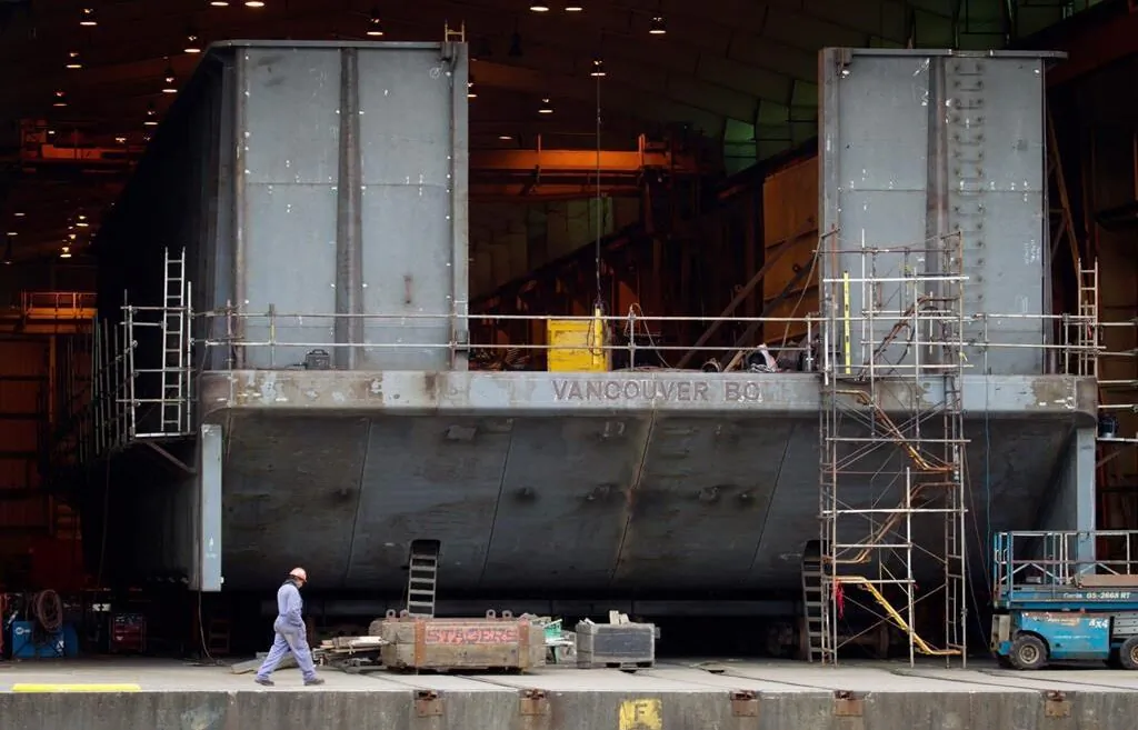 A Seaspan Vancouver Shipyards worker walks past a barge under construction in North Vancouver, B.C., on Nov. 2, 2011. (Darryl Dyck/The Canada Press)