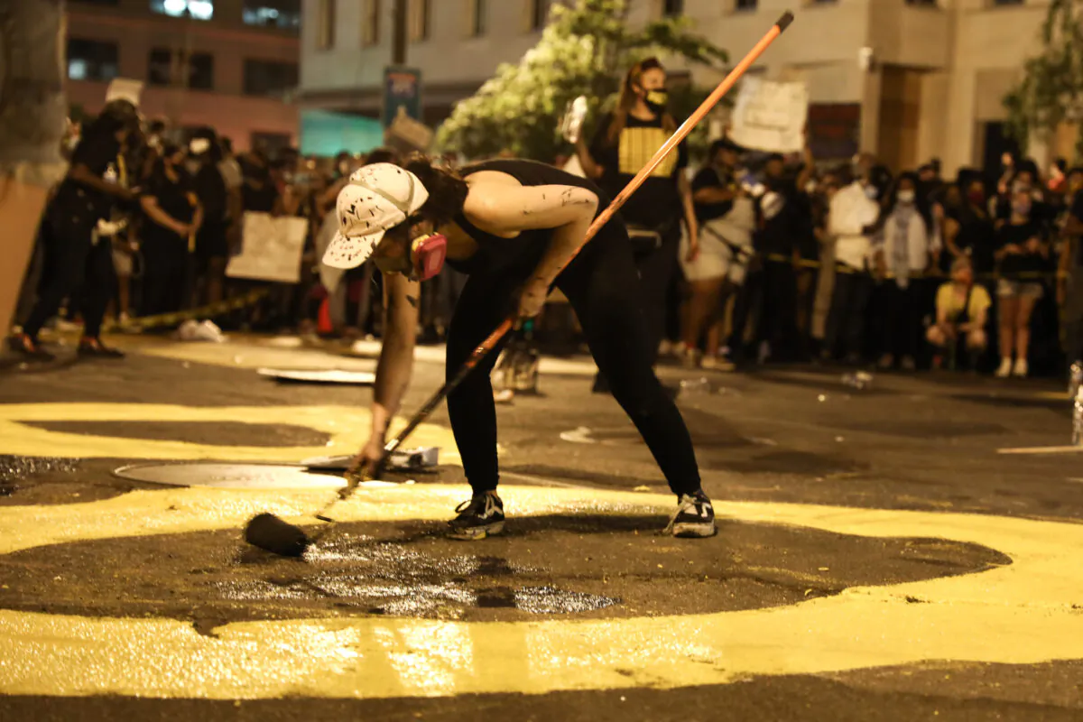 Protesters paint “Defund the Police” on the road during a protest near the White House following the May 25 death of George Floyd in police custody, in Washington on June 6, 2020. (Charlotte Cuthbertson/The Epoch Times)