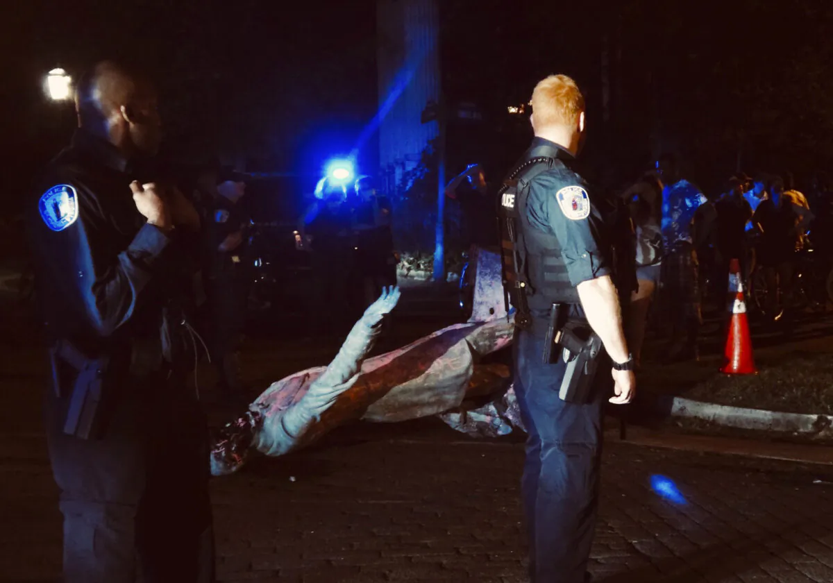 A police officer looks toward the toppled statue of Confederate President Jefferson Davis along Monument Drive, in Richmond, Va., on June 10, 2020. (@thicketoftrash via AP)