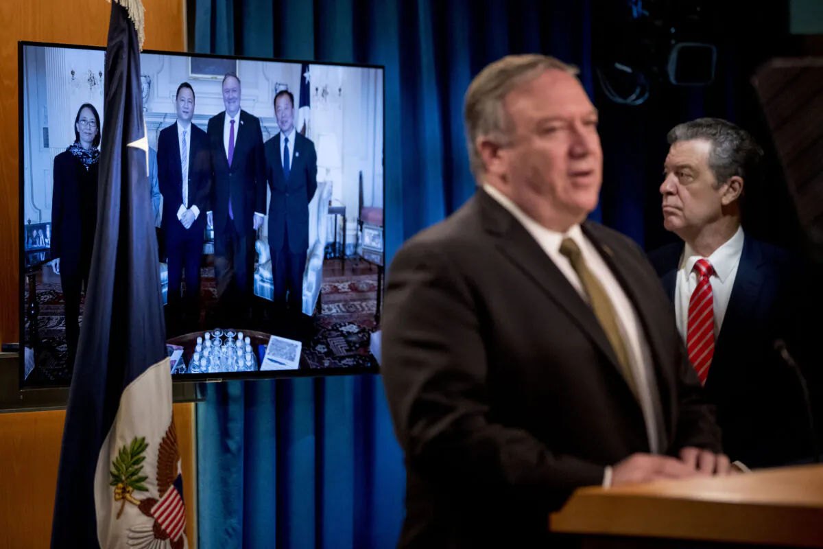 An image of survivors of the 1989 Tiananmen Square protests posing for a photograph with US Secretary of State Mike Pompeo is displayed as Pompeo, foreground, accompanied by Sam Brownback, Ambassador at Large for International Religious Freedom(R), speaks at a news conference at the State Department in Washington on June 10, 2020. (ANDREW HARNIK/POOL/AFP via Getty Images)