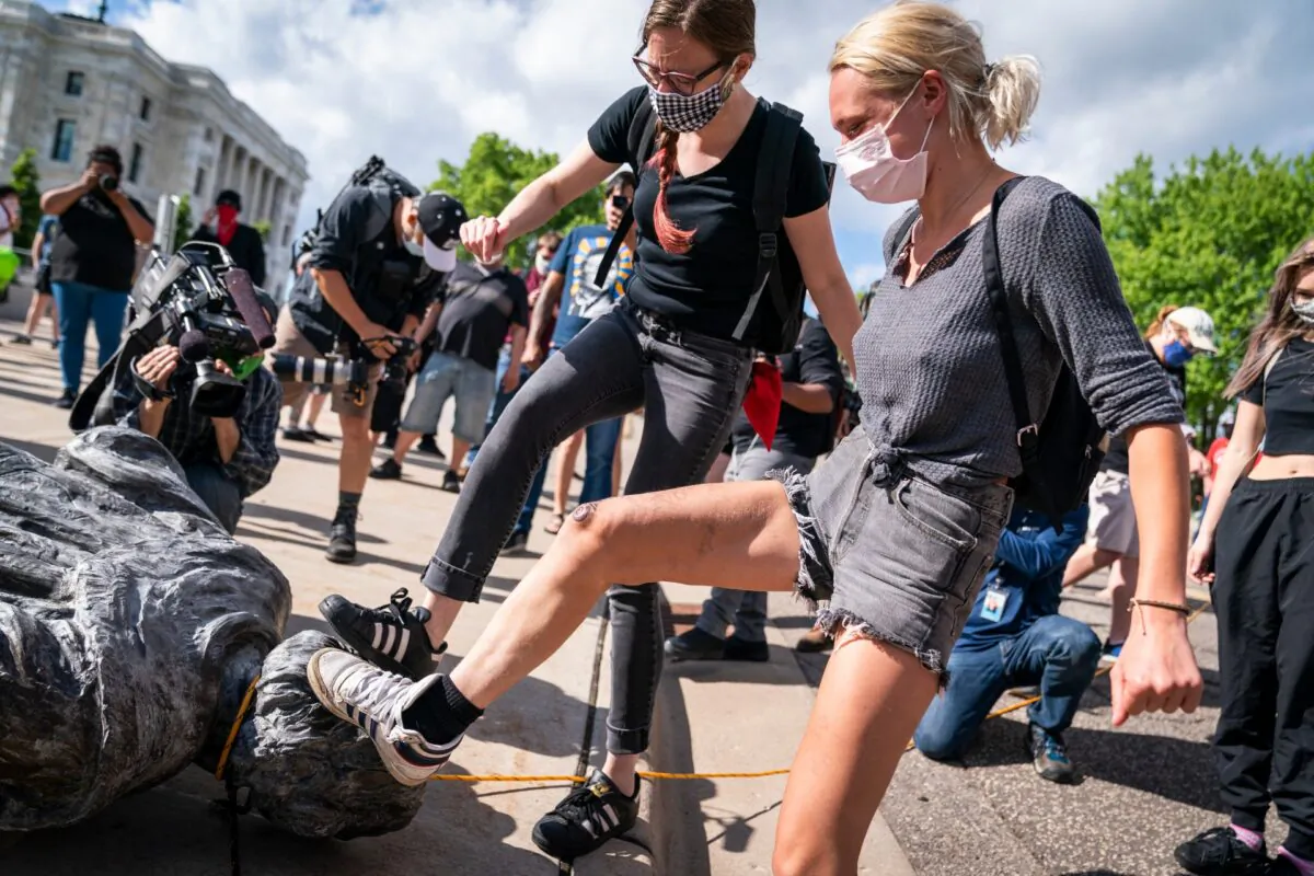 People take turns stomping the Christopher Columbus statue after it was toppled in front of the Minnesota State Capitol in St. Paul, Minn., on  June 10, 2020. (Leila Navidi/Star Tribune via AP)