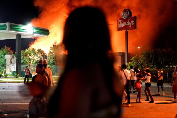 People watch as a Wendy’s burns
