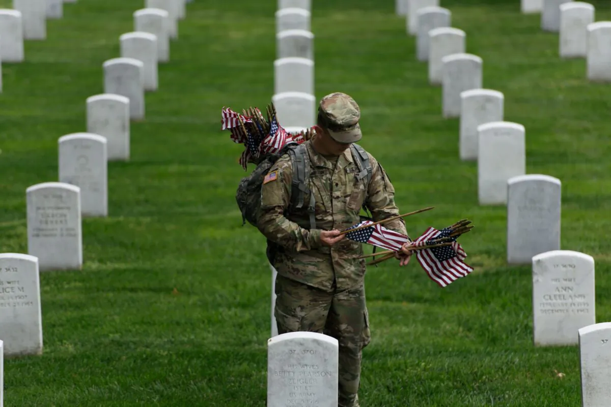 A member of the U.S. Army places an American flag on a grave at Arlington National Cemetery in Arlington, Virginia, in preparation for Memorial Day, on May 25, 2017. (Brendan Smialowski/AFP via Getty Images)