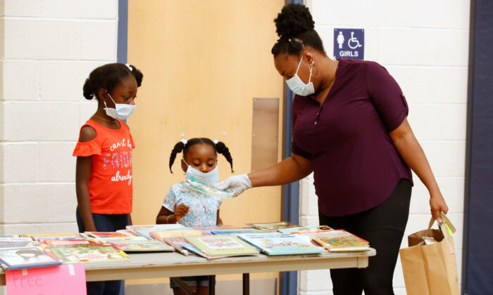 A parent and her children look over the free book table after picking up their personal belongings that have been put in a paper bag in the gym at Freedom Preparatory Academy in Provo, Utah, on May 18, 2020. (George Frey/Getty Images)