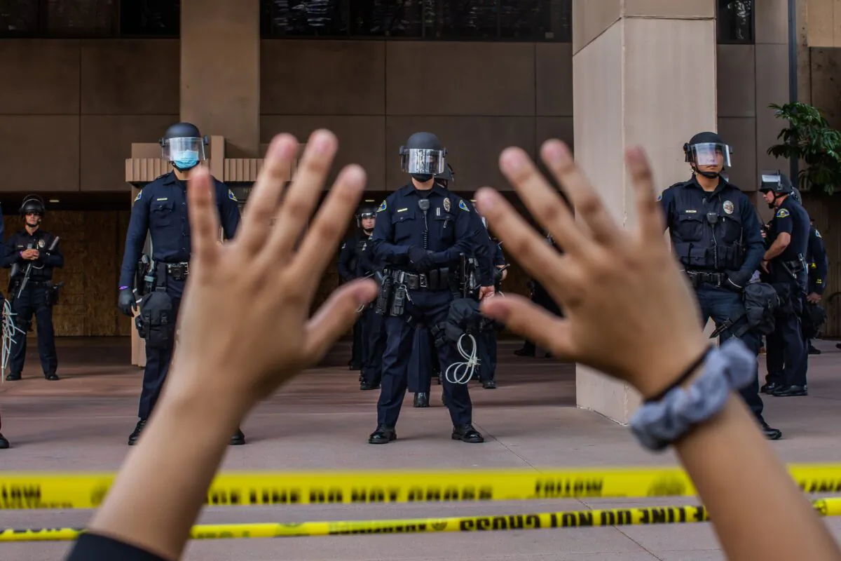 A demonstrator at a protest over the death of George Floyd holds her hands up while she kneels in front of the police at City Hall in Anaheim, Calif., on June 1, 2020. (Apu Gomes/AFP via Getty Images)
