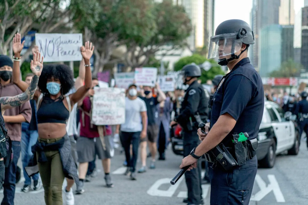 Protesters march past LAPD officers during a demonstration over the death of George Floyd in downtown Los Angeles, Calif., June 6, 2020. (Kyle Grillot/AFP via Getty Images)