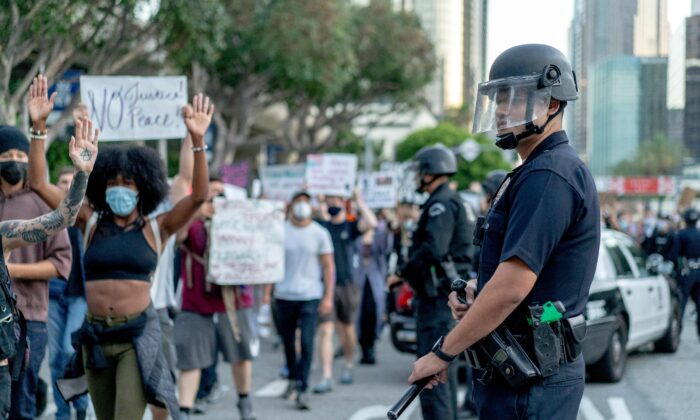 Protesters march past LAPD officers during a demonstration over the death of George Floyd in downtown Los Angeles, Calif., June 6, 2020. (Kyle Grillot/AFP via Getty Images)