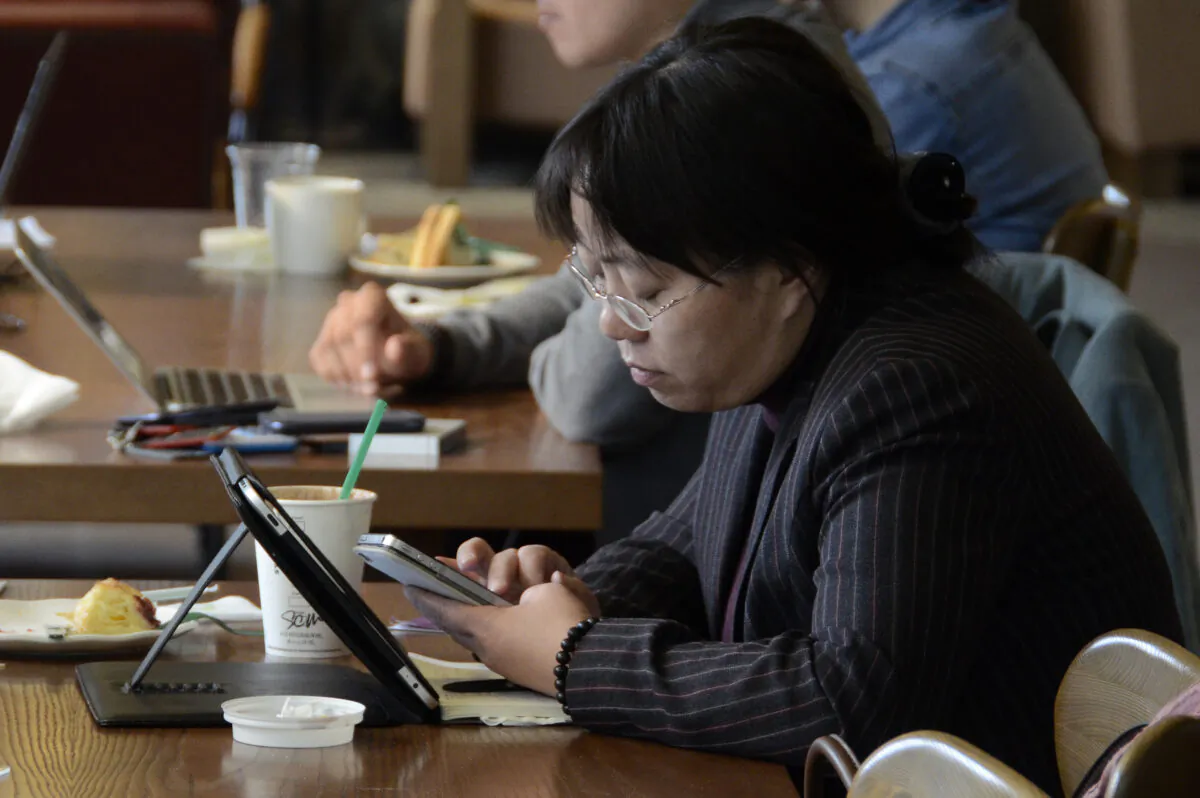A woman reads her phone and tablet at a cafe in Beijing, on November 2, 2012. (WANG ZHAO/AFP via Getty Images)