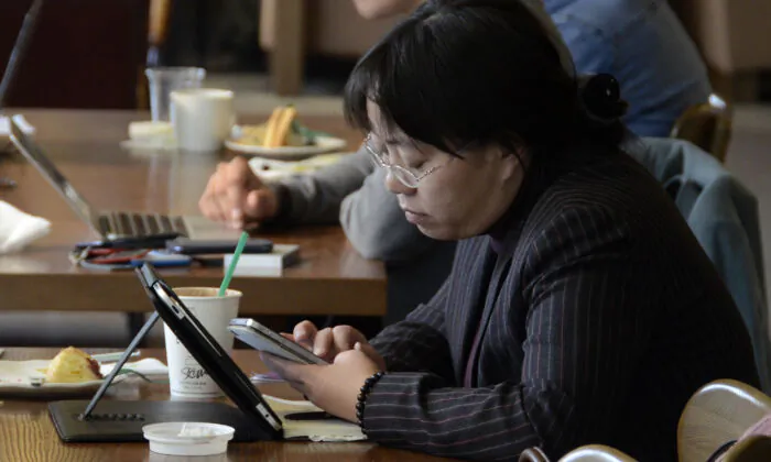 A woman reads her phone and tablet at a cafe in Beijing, on November 2, 2012. (WANG ZHAO/AFP via Getty Images)