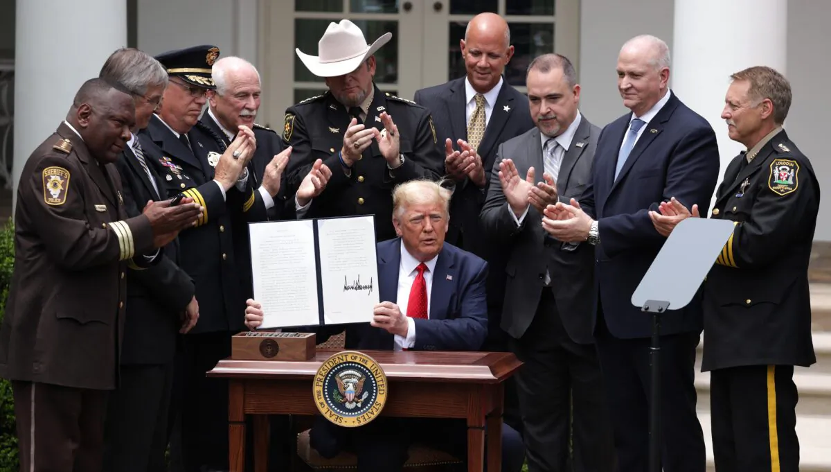 Surrounded by members of law enforcement, President Donald Trump holds up an executive order he signed on “Safe Policing for Safe Communities” during an event in the Rose Garden at the White House on June 16, 2020. (Alex Wong/Getty Images)