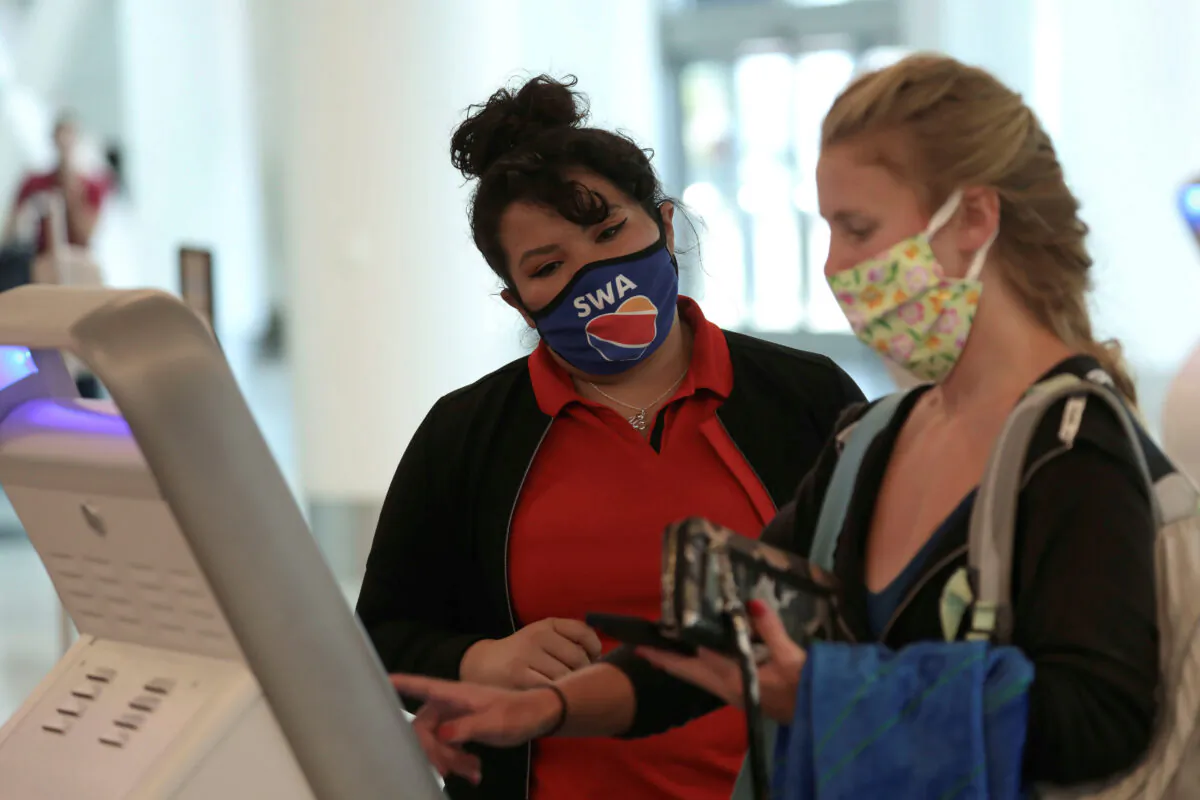 A Southwest Airlines employee wears a protective mask while assisting a passenger at Los Angeles International Airport (LAX) during the COVID-19 outbreak in Los Angeles, Calif., on May 23, 2020. (Patrick T. Fallon/Reuters)