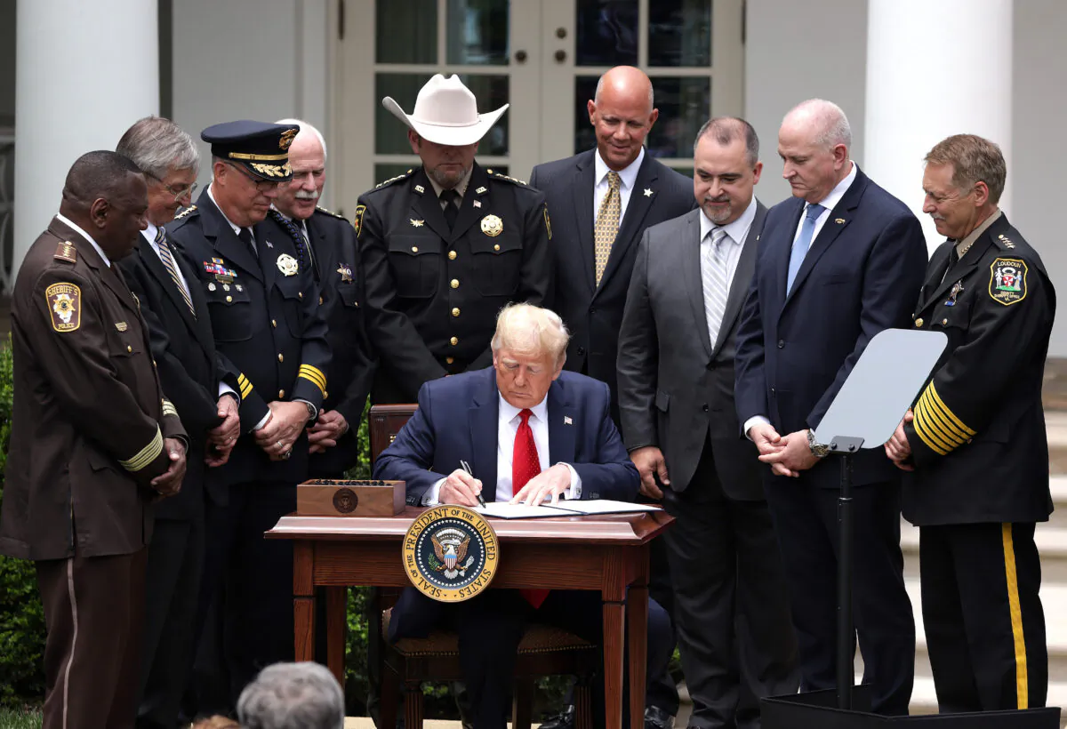 Surrounded by members of law enforcement, President Donald Trump signs an executive order on "Safe Policing for Safe Communities" during an event in the Rose Garden at the White House on June 16, 2020. (Alex Wong/Getty Images)