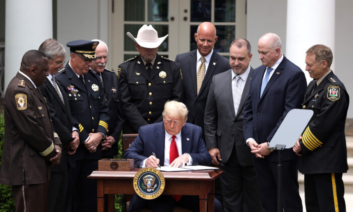 Surrounded by members of law enforcement, President Donald Trump signs an executive order on "Safe Policing for Safe Communities" during an event in the Rose Garden at the White House on June 16, 2020. (Alex Wong/Getty Images)