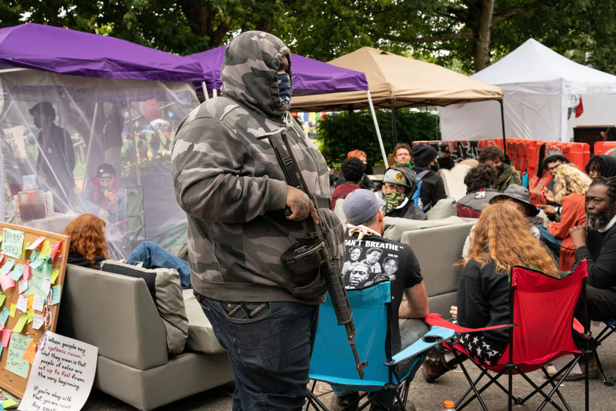 A man walks by the Conversation Cafe while carrying a firearm in the police-free zone known as the Capitol Hill Autonomous Zone (CHAZ), in Seattle on June 15, 2020. (David Ryder/Getty Images)