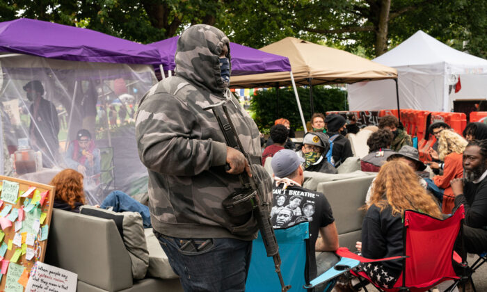 A man walks by the Conversation Cafe while carrying a firearm in the police-free zone known as the Capitol Hill Autonomous Zone (CHAZ), in Seattle on June 15, 2020. (David Ryder/Getty Images)