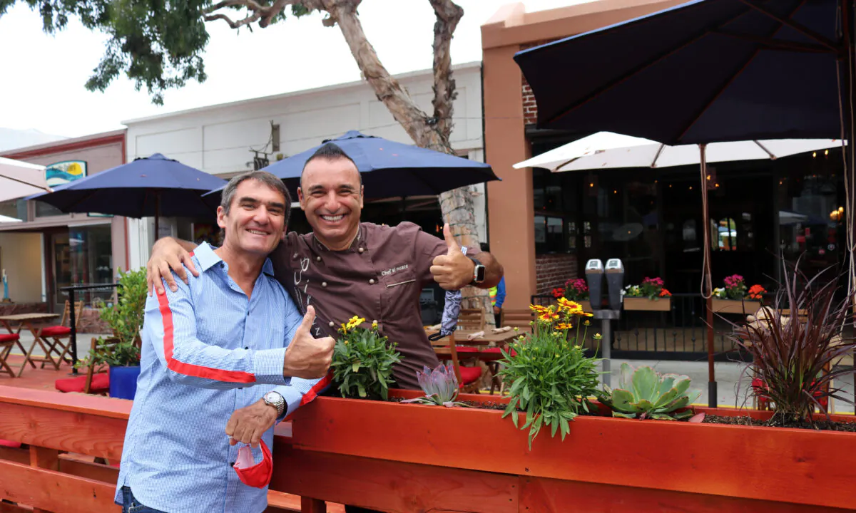 Happy restaurant owners Laurent Vrignaud (L) and Alessandor Pirozzi celebrate the opening of the promenade in Laguna Beach, Calif., on June 15, 2020. (Jamie Joseph/The Epoch Times)