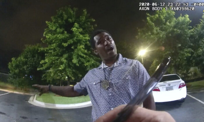 This screen grab taken from body camera video provided by the Atlanta Police Department shows Rayshard Brooks speaking with Officer Garrett Rolfe as Rolfe writes notes during a field sobriety test in the parking lot of a Wendy's restaurant, in Atlanta, Ga., on June 12, 2020. (Atlanta Police Department via AP)