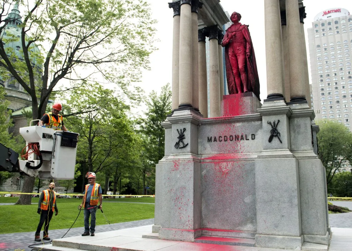 City workers prepare to clean the statue of Sir John A. Macdonald in downtown Montreal on Aug. 17, 2018, after it was vandalized the previous night. (The Canadian Press/Graham Hughes)