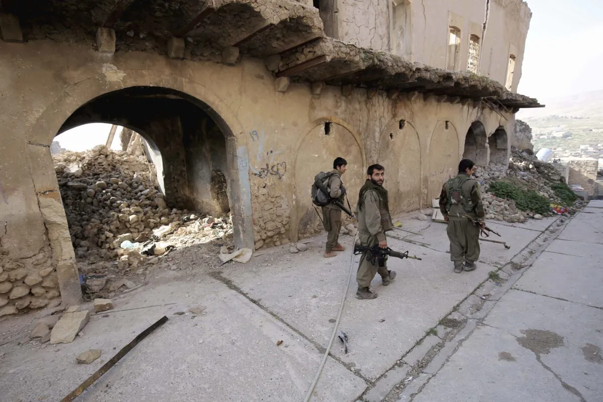 Fighters of the Turkey-based Kurdish Workers' Party (PKK) walk in the damaged streets of Sinjar, Iraq on Jan. 29, 2015. (AP Photo/Bram Janssen, File)