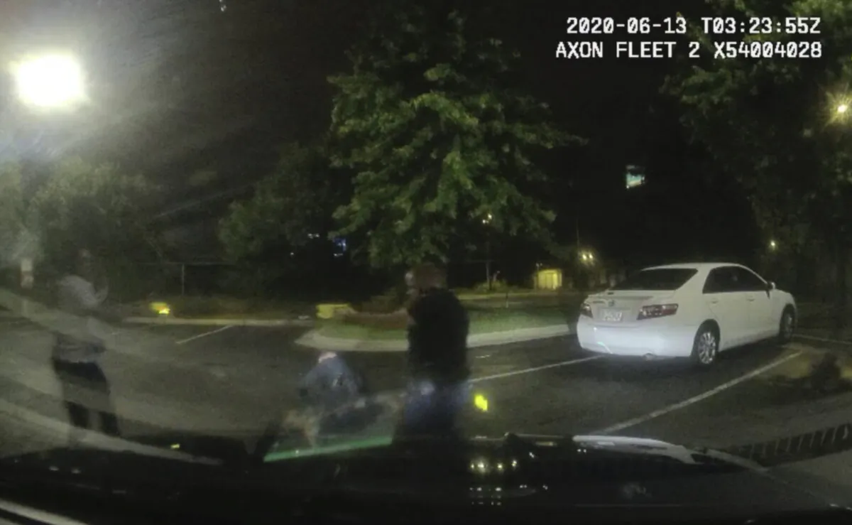 Rayshard Brooks (L) and Officer Garrett Rolfe pointing stun guns at one another, while Officer Devin Brosnan is seen getting up after a struggle among the three men in the parking lot of a Wendy's restaurant, in Atlanta, Ga., early June 13, 2020. (Atlanta Police Department via AP)