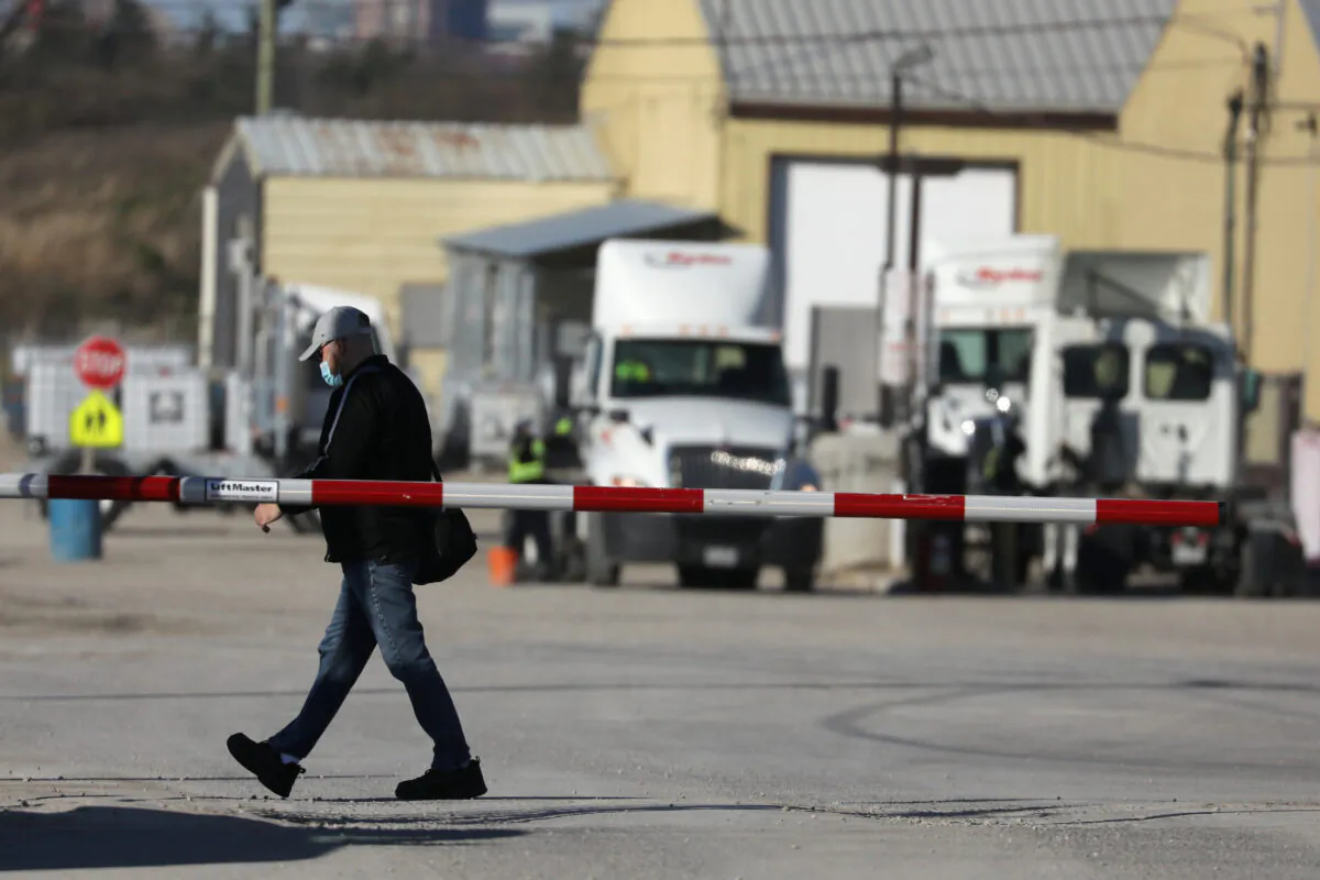 A man wearing a face mask walks past the entry gate after the company said one worker had died and 25 tested positive for the coronavirus disease (COVID-19) at the Maple Lodge Farms chicken processing plant in Brampton, Ontario, Canada on May 7, 2020. (Chris Helgren/Reuters)