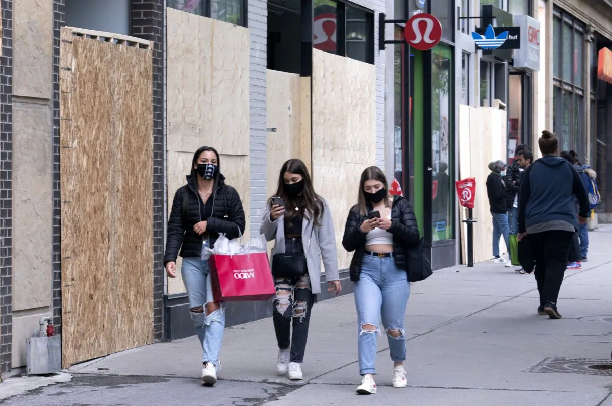 People wear face masks to protect against COVID-19 as they walk along Sainte-Catherine Street in Montreal on June 3, 2020. (Canadian Press/Paul Chiasson)