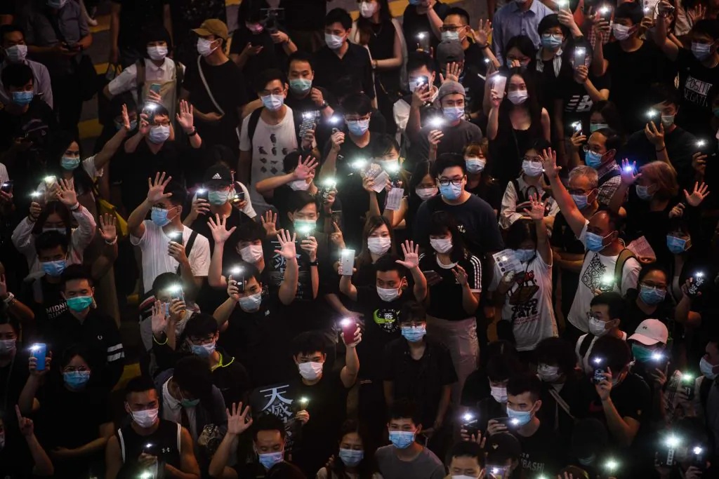 Pro-democracy protesters hold up their mobile phones as they sing during a rally in the Causeway Bay district of Hong Kong on June 12, 2020. (Anthony Wallace/AFP via Getty Images)