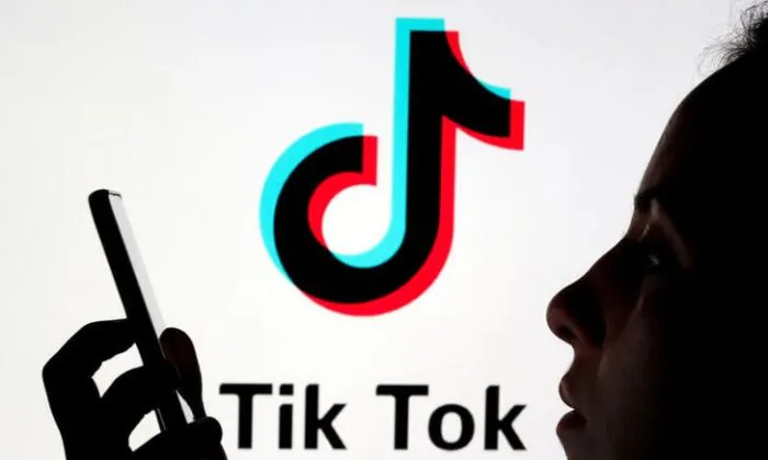 A person holds a smartphone as the Tik Tok logo is displayed behind in this picture illustration taken on Nov. 7, 2019. (Dado Ruvic/Reuters)