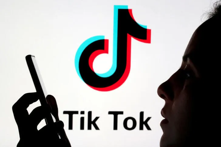 A person holds a smartphone as the Tik Tok logo is displayed behind in this picture illustration taken on Nov. 7, 2019. (Dado Ruvic/Reuters)