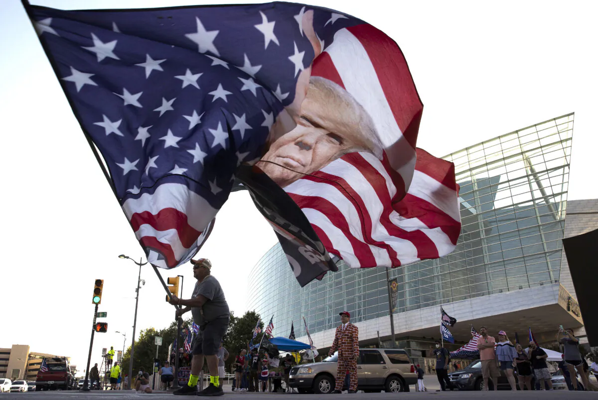 Trump supporter Randall Thom waves a giant Trump flag to passing cars outside the BOK Center in Tulsa, Okla., on June 18, 2020. (Win McNamee/Getty Images)
