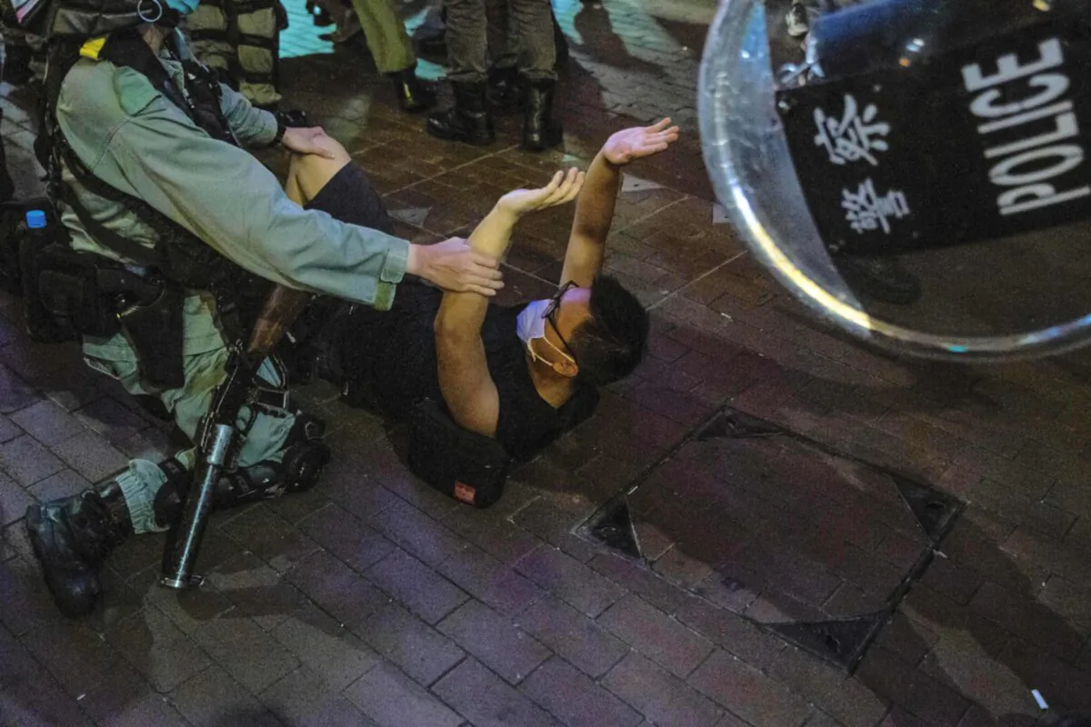 A police officer (L) detains a man (C) as protesters gathered in the Mong Kok district of Hong Kong on June 12, 2020. (Isaac Lawrence/AFP via Getty Images)