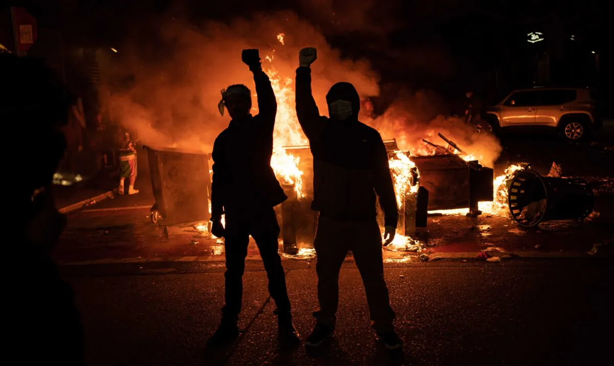 Protesters raise their fists as a fire burns in the street after clashes with law enforcement near the Seattle Police Department's East Precinct, in Seattle, on June 8, 2020. (David Ryder/Getty Images)