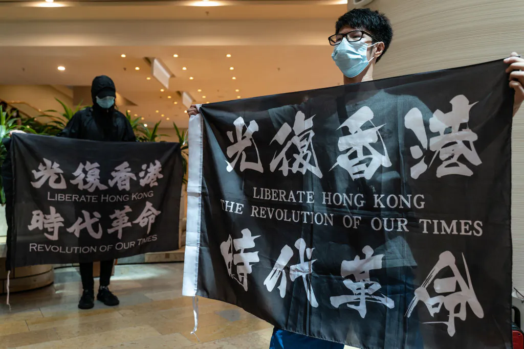 Pro-democracy supporters hold banners and shout slogans as they gather in a shopping mall during a lunch protest in Hong Kong on June 12, 2020. (Anthony Kwan/Getty Images)