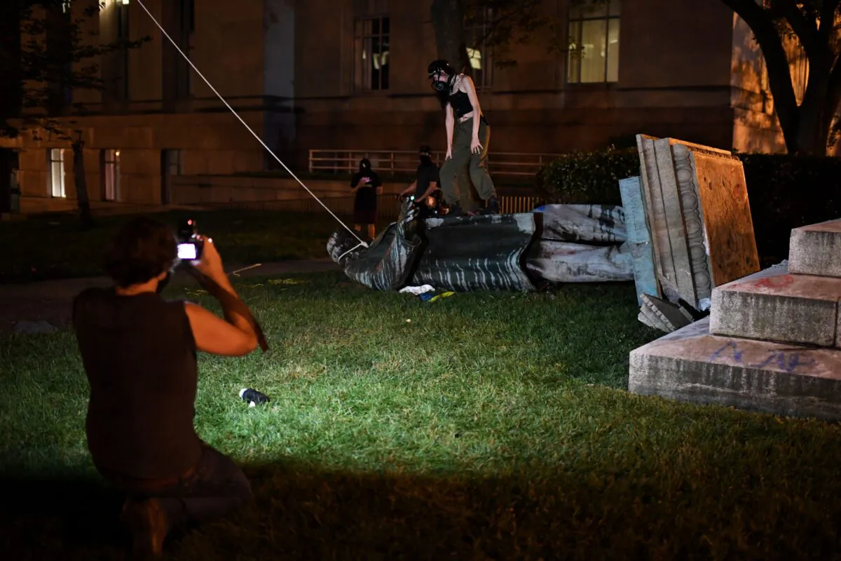 People stand around and take pictures with the statue of Confederate general Albert Pike after it was toppled by protesters at Judiciary square in Washington on late June 19, 2020. (ERIC BARADAT/AFP via Getty Images)