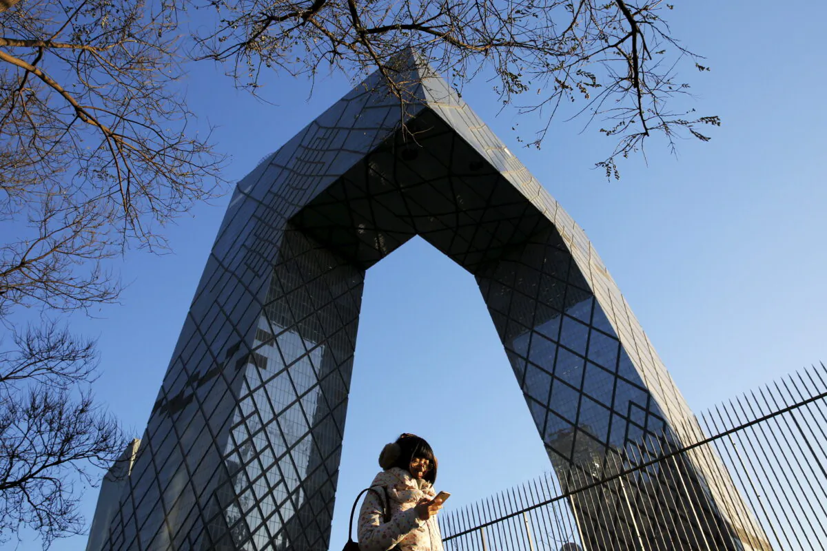 A morning commuter walks in front of the China Central Television (CCTV) building on a sunny day Dec. 2, 2015, after a fresh cold front cleared the smog that was blanketing Beijing. (Reuters/Damir Sagolj)