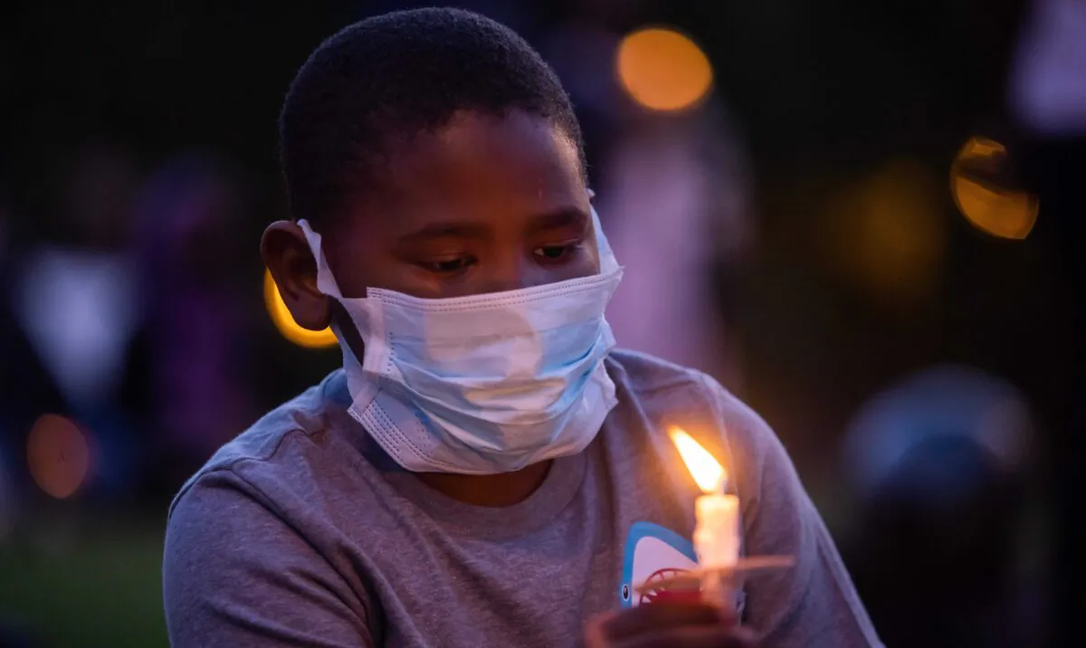 A boy holds a candle during a vigil around a makeshift memorial at the tree where Robert Fuller was found dead to demand a full investigation into Fuller's death, in Palmdale, Calif., on June 13, 2020. (Apu Gomes/AFP via Getty Images)