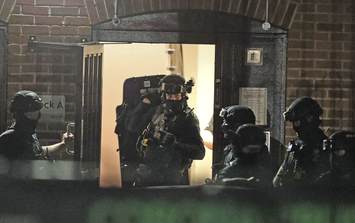Armed police officers work at a block of flats off Basingstoke Road in Reading after an incident at Forbury Gardens park in the town centre of Reading, England, Saturday on June 20, 2020. (Steve Parsons/PA via AP)