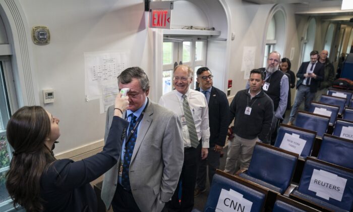 Workers from the White House Physician's Office check the body temperatures of journalists in the press briefing room at the White House in Washington on March 17, 2020. (Drew Angerer/Getty Images)