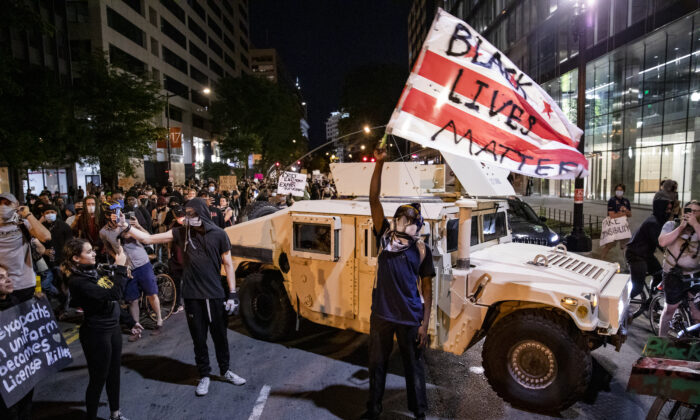 A protester waves a DC flag with “Black Lives Matter” spray painted on it next to a DC National Guard Humvee during a demonstration over the death of George Floyd, who died in police custody, in Washington on June 2, 2020. (Samuel Corum/Getty Images)