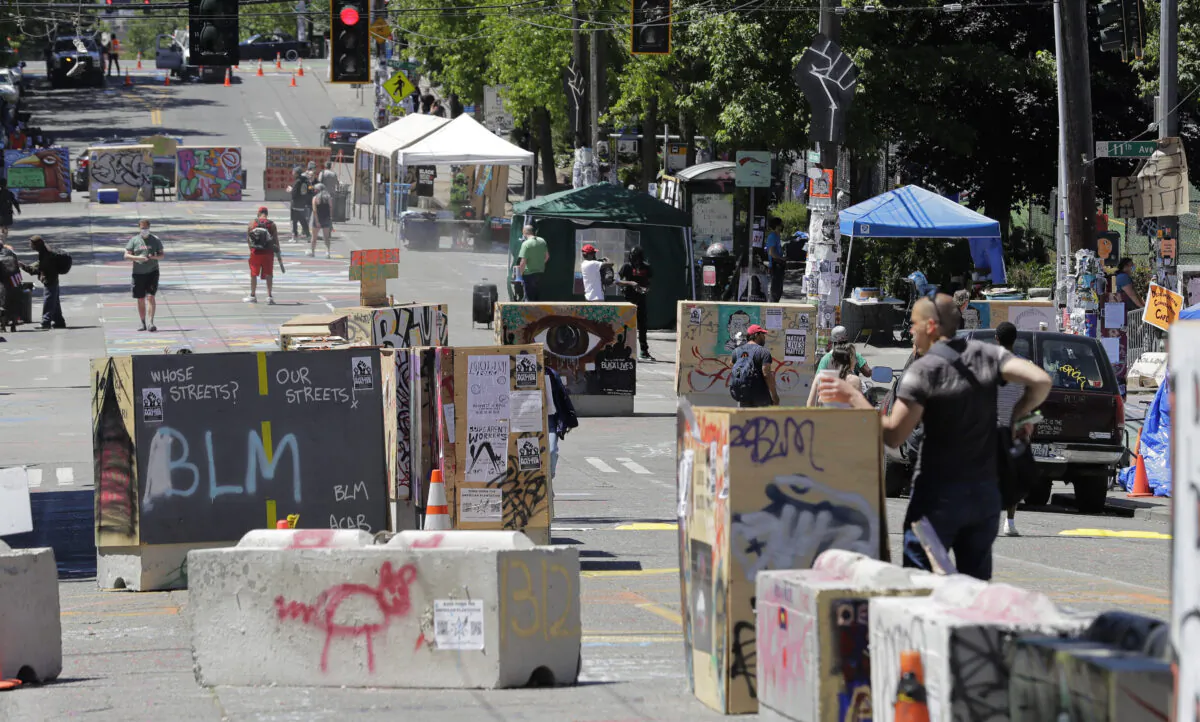 People walk amidst barricades in what has been named the Capitol Hill Occupied Protest zone in Seattle on June 22, 2020. (AP Photo/Ted S. Warren)