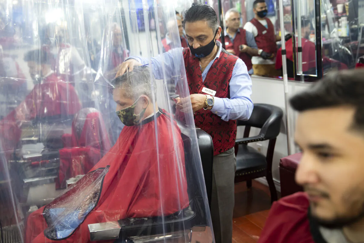 Peter Shamuelov (C) wears a protective mask as he gives a haircut to a customer at Ace of Cuts barbershop, in New York City, N.Y., on June 22, 2020. (John Minchillo/AP Photo)