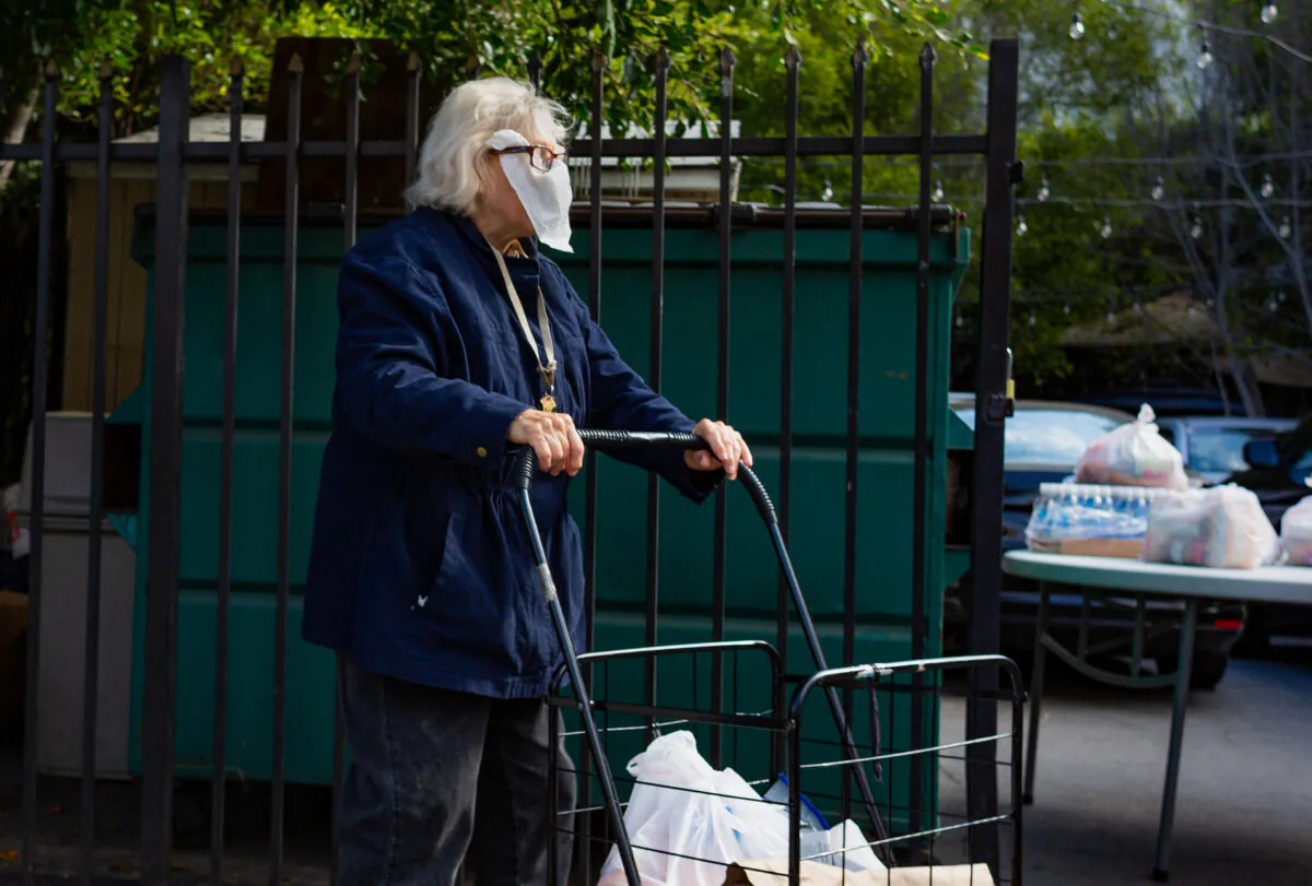 An elderly woman wearing a napkin for a mask walks on a sidewalk near her home in Los Angeles, Calif., on June 22, 2020. (John Fredricks/The Epoch Times)