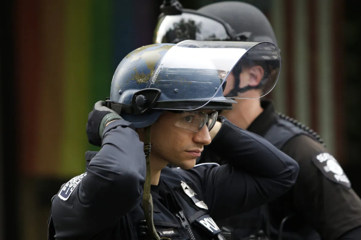 A police officer adjusts his helmet at a barricade outside the Seattle Police Department’s East Precinct in Seattle, Wash., on June 2, 2020. (Jason Redmond/AFP/Getty Images)