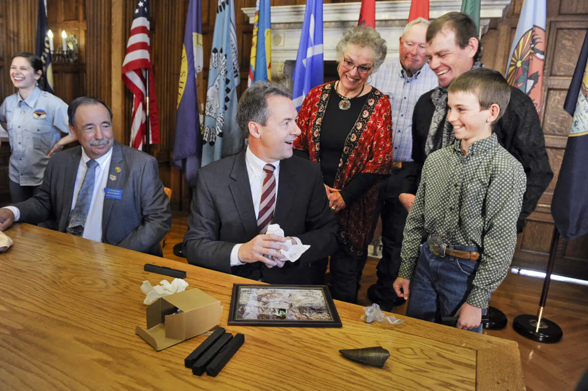 Montana Gov. Steve Bullock accepts a fossilized rib and tail vertebrae from a triceratops from Luke Phipps, 12, at the State Capitol in Helena, Mont., on April 16, 2016 (Thom Bridge/Independent Record/AP)