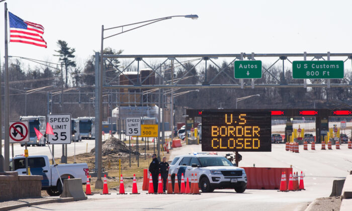 U.S. Customs officers stand beside a sign saying that the U.S. border is closed at the U.S.-Canada border in Lansdowne, Ont., on March 22, 2020. (Lars Hagberg/AFP via Getty Images)