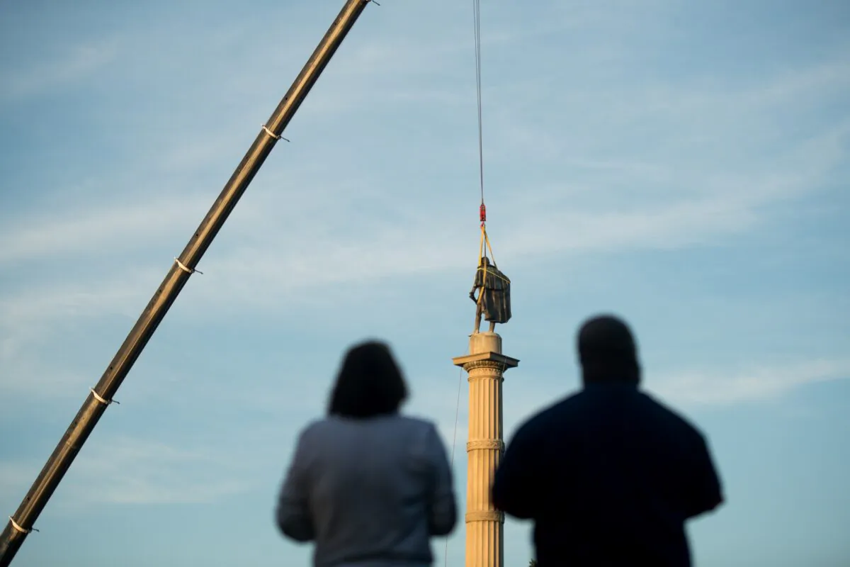 People look at the statue of John C. Calhoun atop the monument in his honor as workers prepare to relocate the memorial from Marion Square in Charleston, S.C., on June 24, 2020. (Sean Rayford/Getty Images)