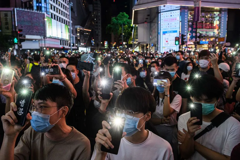 Pro-democracy activists hold up their mobile phones as they sing during a rally in the Causeway Bay district of Hong Kong on June 12, 2020. (Anthony Wallace/AFP via Getty Images)