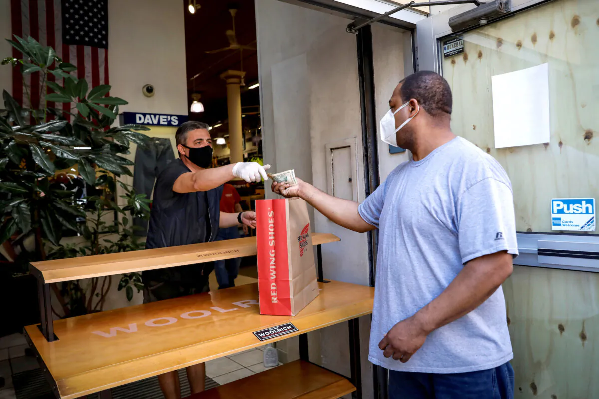 A customer pays for his purchase in the doorway of Dave's New York, a retail store, in New York City, on June 8, 2020. (Brendan McDermid/Reuters)
